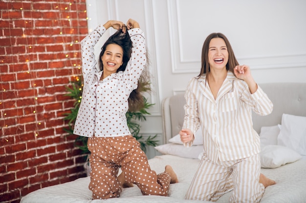 Chicas felices. Dos niñas en pijama divirtiéndose en el dormitorio