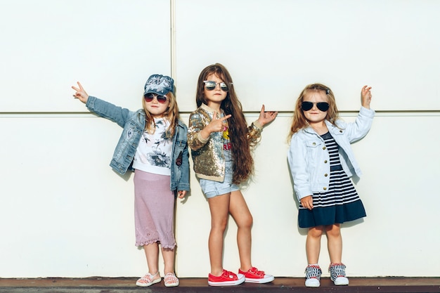 Chicas frescas con gafas de sol frente a la pared blanca.