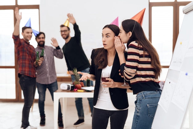 Las chicas con gorros festivos están hablando en la oficina.