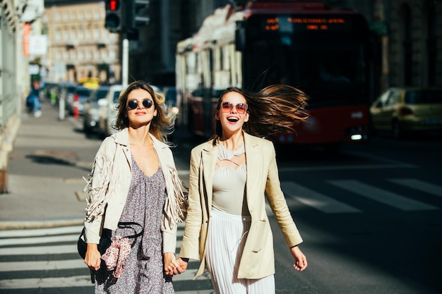 Chicas guapas caminando en la calle al aire libre y divirtiéndose mejores amigas estilo urbano de la ciudad dos amigos...