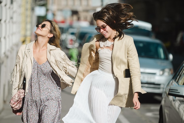 Chicas guapas corriendo en la calle al aire libre y divirtiéndose. Las mejores amigas riéndose de la ciudad urbana.
