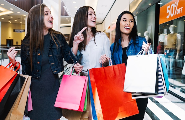 Chicas guapas explorando tiendas en el centro comercial