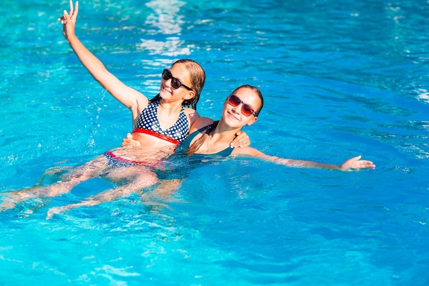 Chicas guapas felices divirtiéndose en la piscina del resort