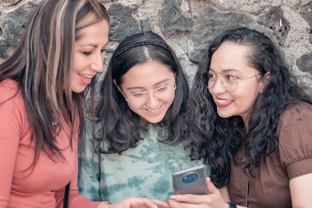 Chicas guapas y jóvenes divirtiéndose y mirando sus teléfonos celulares tomando fotos y caminando por la ciudad felices y sonrientes en un día soleado