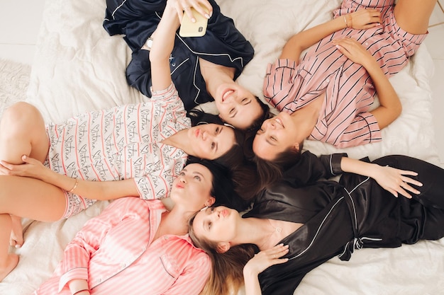 Chicas guapas en pijama tomando selfie en la cama