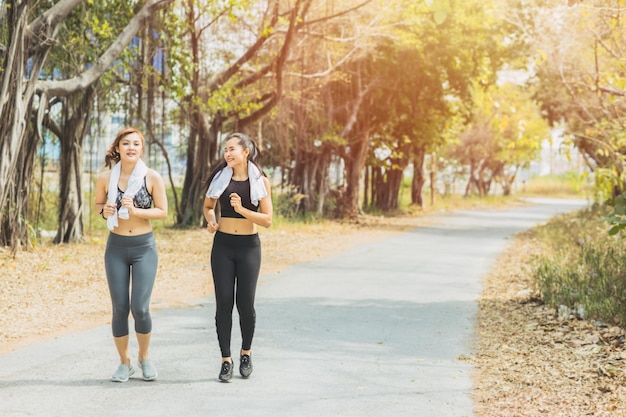 Chicas haciendo ejercicio al aire libre en el parque verde Dos hermosas amigas asiáticas corriendo al aire libre