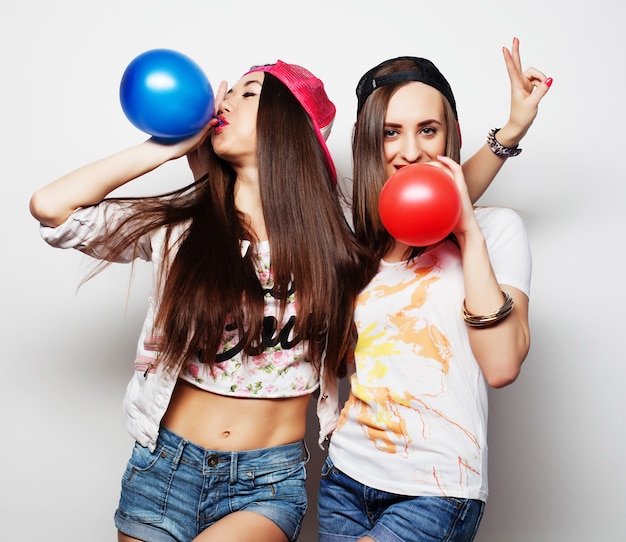 Chicas hipster sonriendo y sosteniendo globos de colores