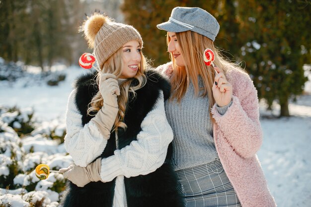 chicas jóvenes y con estilo en la ropa de invierno están caminando en el parque solar con candyes