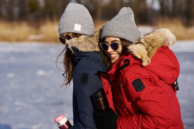 Unas chicas jóvenes de moda caminan y se divierten al aire libre en invierno.