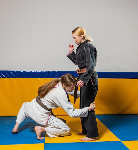 Las chicas jóvenes practican jiu jitsu brasileño en el gimnasio