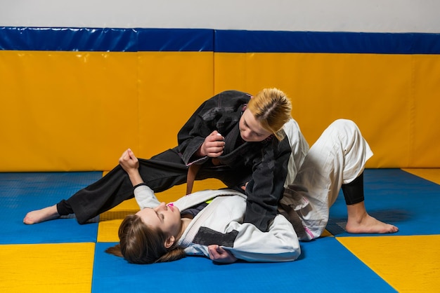 Las chicas jóvenes practican jiu jitsu brasileño en el gimnasio