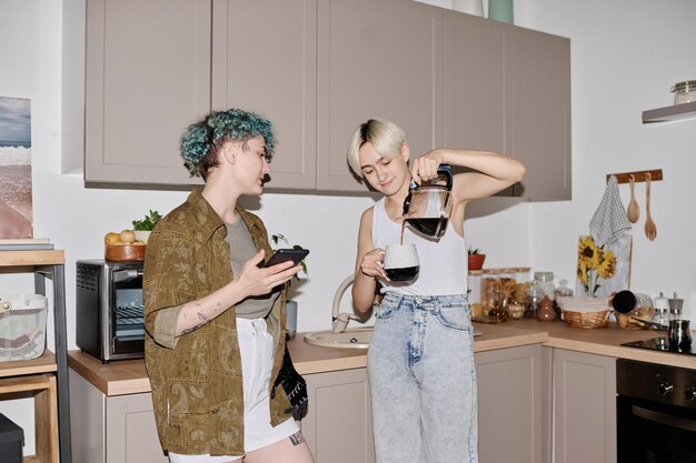 Chicas jóvenes tomando café juntas en la cocina de casa