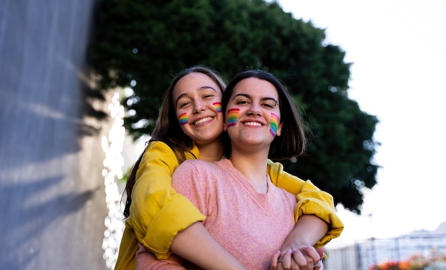 chicas lesbianas que se divierten pintándose y con la bandera lgtb en el día del orgullo concepto lgtb