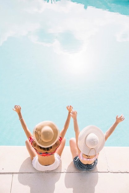 Foto chicas levantando los brazos enfrente de piscina