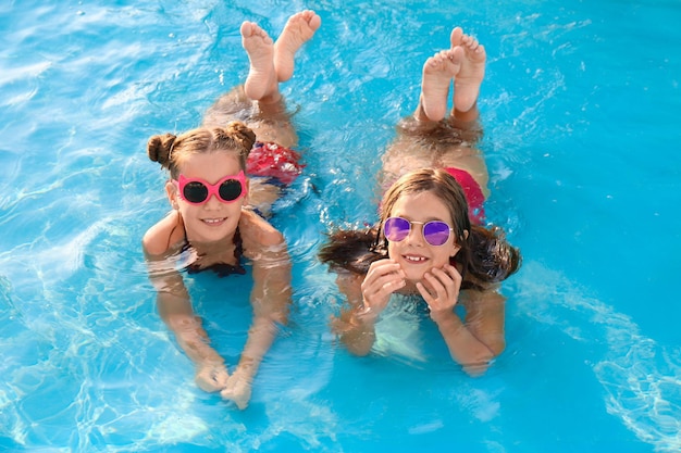 Chicas lindas felices en la piscina en un día soleado