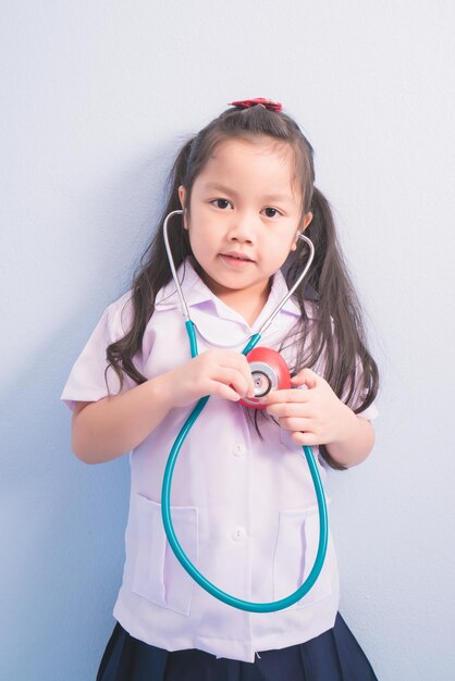 Foto chicas lindas y felices con uniforme médico blanco y estetoscopio en el cuello actúan como doctores.