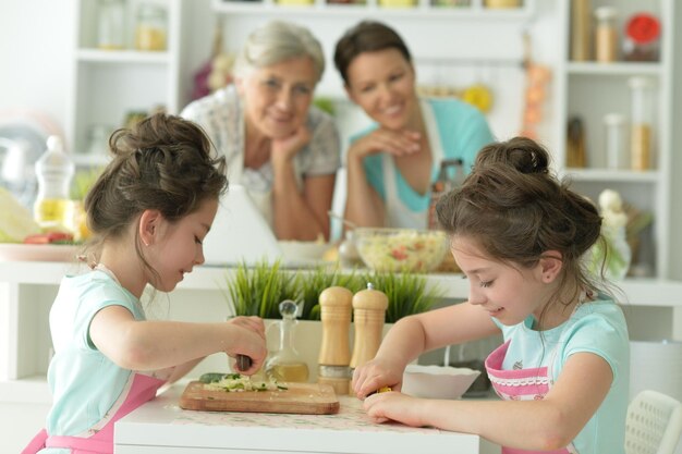 Chicas lindas preparando deliciosa ensalada fresca en la cocina madre y abuela