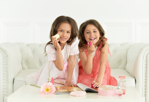 Chicas lindas con revista y cosméticos en casa.