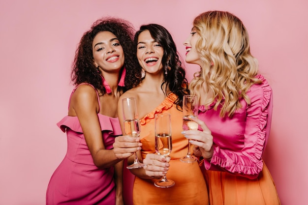 Foto chicas de moda levantando copas foto de estudio de amigos riéndose bebiendo champán