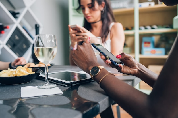 Chicas multiétnicas bebiendo y charlando con smartphone