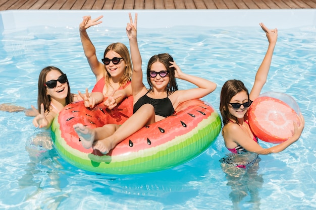 Chicas en la piscina mostrando el signo de paz