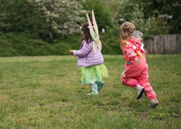 Foto chicas que corren jugando a las chicas de la feria de la amistad cuento unicornio botas de lluvia abrigo de lluvia chicas que saltan enérgicas