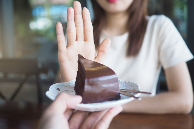 Una de las chicas de la salud usó una mano para empujar un plato de pastel de chocolate.