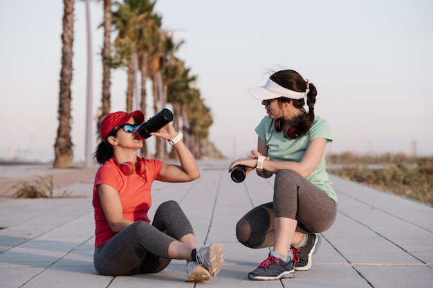 Foto chicas sentadas en el suelo y hablando después del entrenamiento.