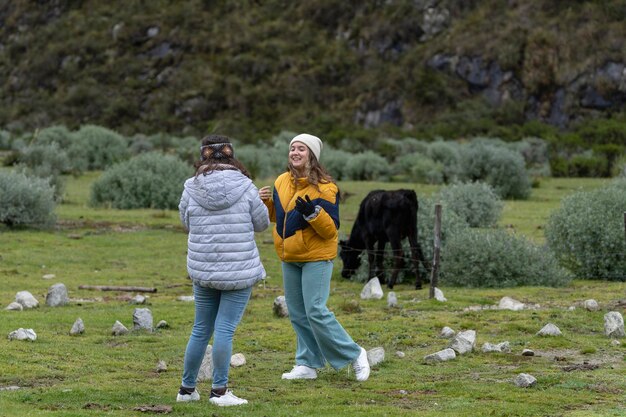 Chicas sonriendo y hablando junto a una vaca en la montaña