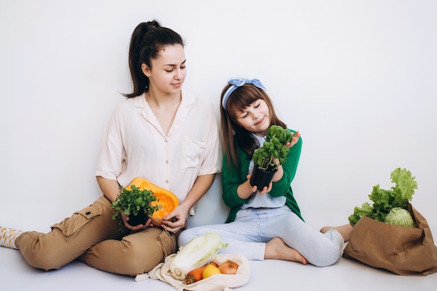 Chicas sonrientes con una bolsa de papel ecológico de verduras y verduras saludables, aisladas en blanco. Concepto de alimentación saludable. Concepto de desperdicio cero. Compra de alimentos sin empaque. Bolsa natural ecológica con fr orgánico