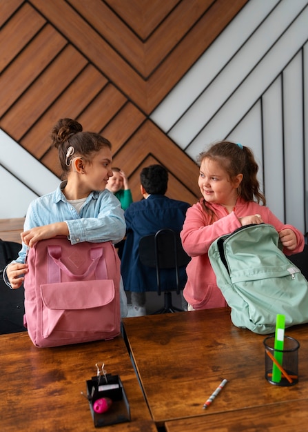 Foto chicas sonrientes de tiro medio en la escuela