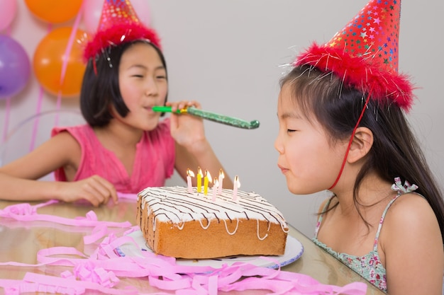 Chicas soplando noisemaker y velas de cumpleaños