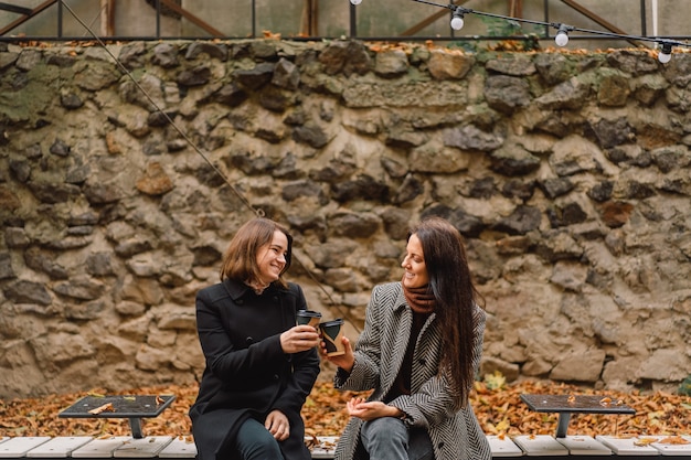 Chicas tomando café en el parque. Amigos y estilo de vida