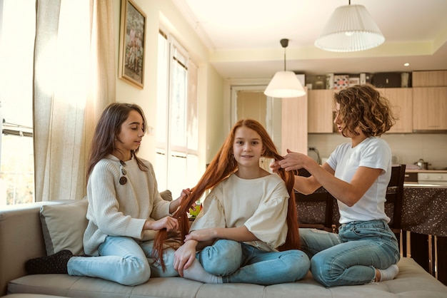 Foto chicas trenzando el cabello de su amiga