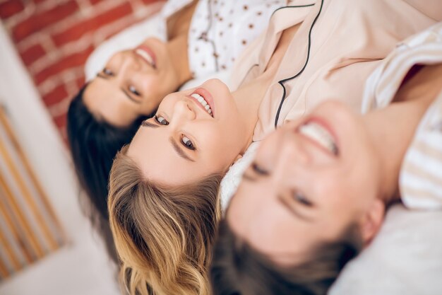 Chicas. Tres hermosas chicas acostado en la cama y sonriendo