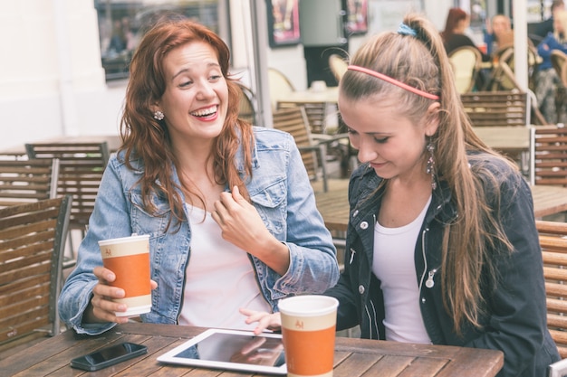 Chicas usando tableta digital en el café