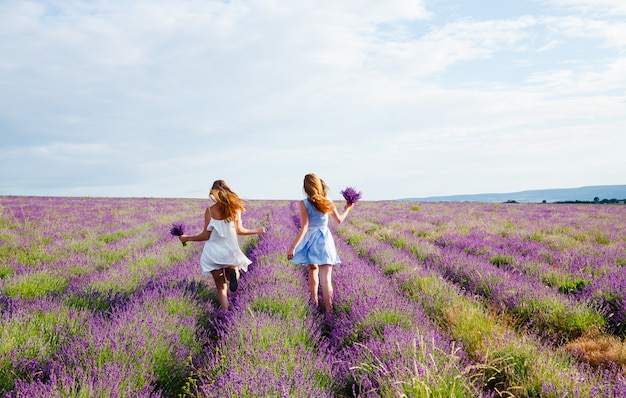 Chicas en vestidos corriendo por un campo de lavanda