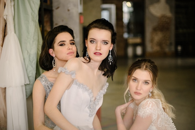 Chicas en vestidos de novia blancos están posando.