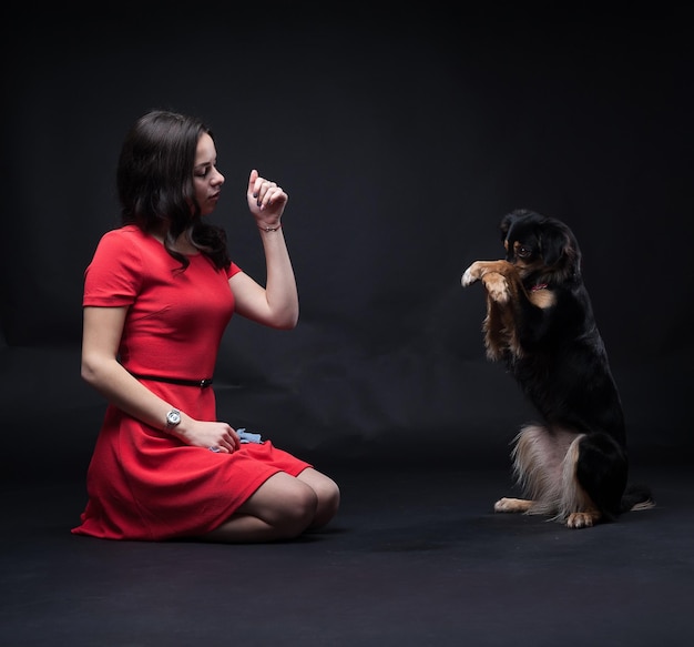 Chicas en vestidos rojos con perros sobre fondo negro