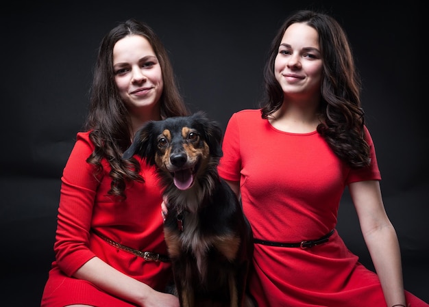 Chicas en vestidos rojos con perros sobre fondo negro