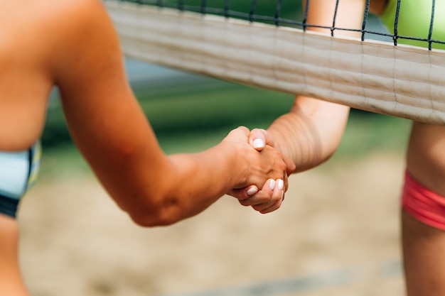 Chicas de voleibol de playa dándose la mano después del partido