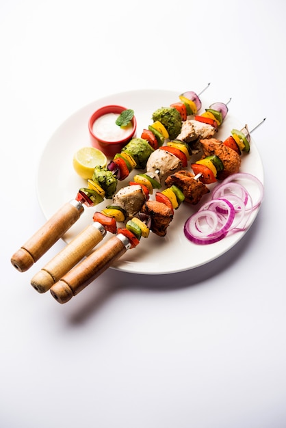 Chicken Hariyali Kakab oder Malai Malai Kebab in Tricolor serviert mit Spießen und Joghurt-Dip in einem Teller