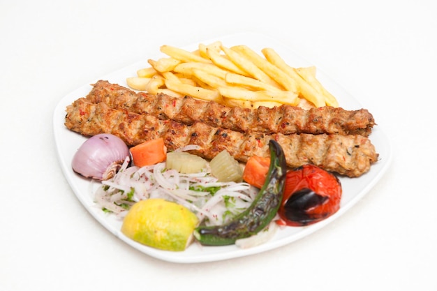 Chicken Kabab mit Pommes-Salat-Tomaten-Zwiebeln serviert in einem Gericht isoliert auf grauem Hintergrund Seitenansicht von Fastfood