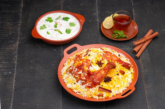 Chicken Mandi Biryani mit Raita als Beilage im Steingut angerichtet