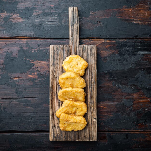 Chicken Nuggets gebraten auf dunklem Holzhintergrund, mit Platz für Text.