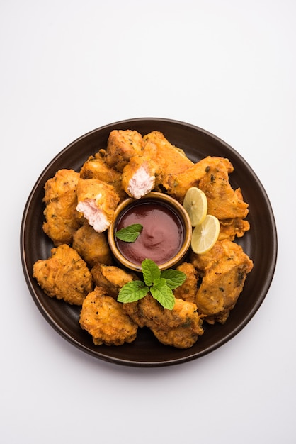 Chicken Pakora oder Pakoda oder Fritters ist ein beliebter indischer Snack, bei dem Hähnchenstücke ohne Knochen mariniert und dann mit einer Mischung aus Besan, Reismehl, Maisstärke und Ei überzogen werden