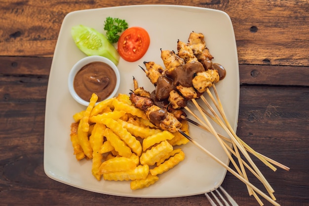 Chicken Satay serviert mit Erdnusssauce und Pommes frites. Bali, Lebensstil