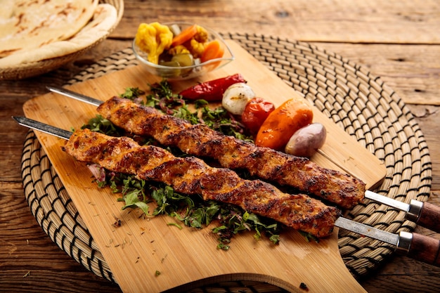 Foto chicken seekh kebab serviert in einem holzschneidebrett isoliert auf holzhintergrund seitenansicht