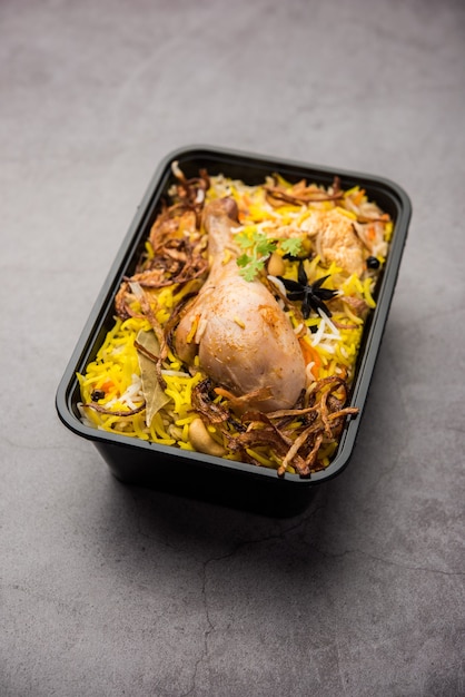 Chicken Tikka Biryani im Restaurantstil verpackt für die Lieferung nach Hause in einer Plastikbox oder einem Behälter mit Raita und Salan