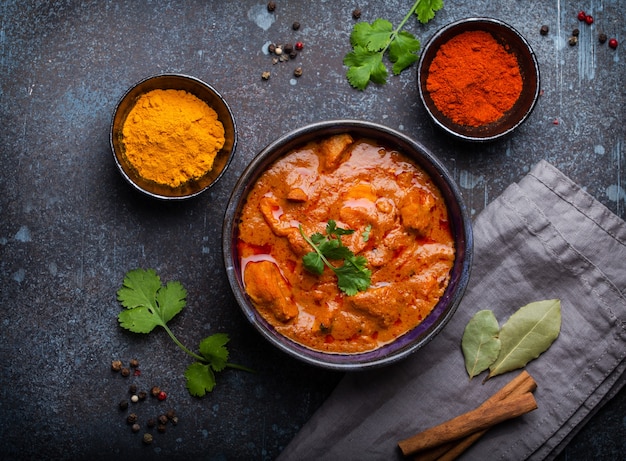 Foto chicken tikka masala mit würzigem curryfleisch serviert in rustikaler keramikschale, beliebtes indisches gericht, auf betonhintergrund, draufsicht